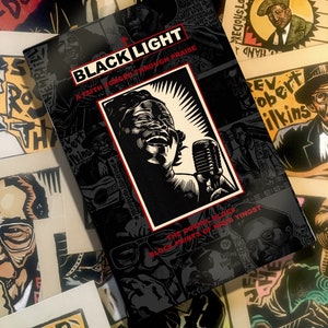May include: A black book with the title "Black Light: A Faith Forged Through Praise" and the subtitle "The Gospel Blues Block Prints of Rev. Yingst". The cover features a black and white illustration of a person singing into a microphone.