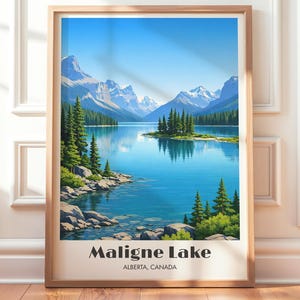Op de afbeelding: Een ingelijste print van Maligne Lake in Alberta, Canada. Het kunstwerk toont een serene meer met bergen en groenblijvende bomen onder een heldere blauwe lucht. De print heeft een licht houten frame en de tekst "Maligne Lake" staat onderaan.