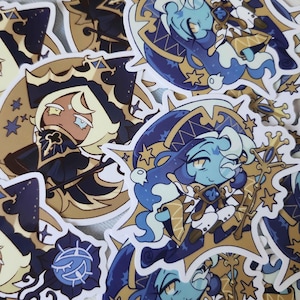 Pode incluir: Uma coleção de autocolantes com personagens de desenhos animados com temas celestiais e de fantasia. Os autocolantes apresentam personagens em azul escuro, dourado e azul claro, com detalhes intrincados e motivos de estrelas. Os personagens usam chapéus ornamentados e seguram cajados.