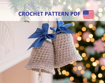 May include: Two light gray crocheted bells hanging side by side, each adorned with a dark blue satin ribbon bow at the top and a small gold bead dangling from the center. The text CROCHET PATTERN PDF is visible at the top of the image.