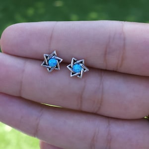 May include: A pair of silver earrings with a blue opal stone in the center of each star of David.