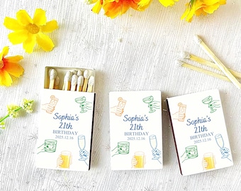May include: Three matchboxes with a white background. The matchboxes have a maroon border and are decorated with illustrations of cocktails and the text "Sophia's 21th Birthday 2025.12.16". One matchbox is open, revealing the matches.