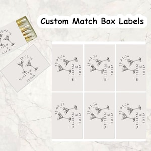 May include: Custom match box labels with a martini glass design. The labels are light gray with black text that reads "WILLIAM & SOFIA" and the date "28.02.26". The image also shows a matchbox.