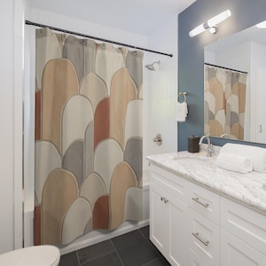 May include: A shower curtain with a repeating pattern of abstract shapes in shades of beige, gray, and rust. The curtain hangs in a bathroom with white fixtures and a dark floor. The design is reminiscent of a mosaic or layered stone.