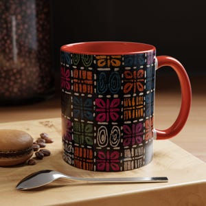 Peut inclure: Un mug en céramique avec un motif géométrique multicolore et vibrant sur fond noir. Le mug présente un intérieur orange vif et une anse assortie. Le design extérieur se compose de carrés répétitifs avec diverses formes abstraites.