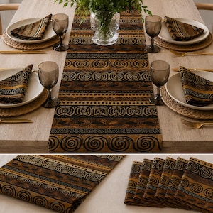 May include: A table runner and matching napkins featuring a repeating pattern of black spiral and geometric shapes on a brown background. The set includes a long rectangular runner and several folded napkins, all displaying the same dark print.