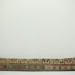 May include: A long, rectangular pillow with a patterned design. The pillow features a beige background with a repeating floral and geometric pattern in shades of red, green, and blue. The pillow is approximately 30 inches long.