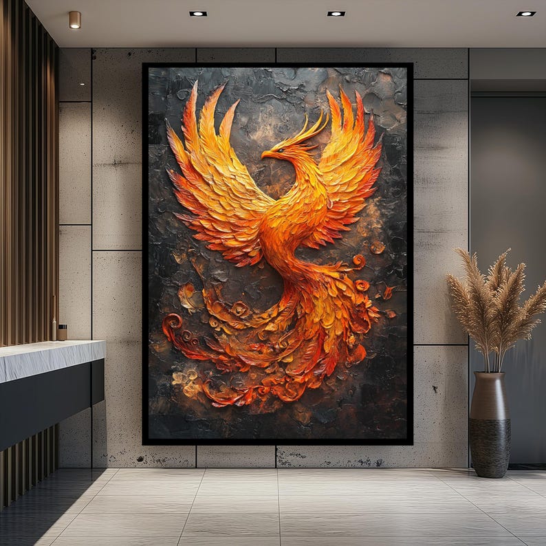 May include: A large framed artwork depicting a phoenix in shades of orange and yellow against a dark background. The phoenix is rendered in a textured, three-dimensional style, with its wings spread wide. The artwork is displayed in a modern interior setting.