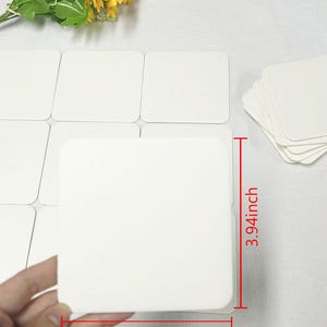May include: A set of 10 white square coasters, each measuring 3.94 inches by 3.94 inches. The coasters are made of a smooth, white material and are perfect for protecting surfaces from spills and scratches.