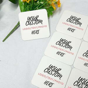 May include: Five white square coasters with black text that reads "Your Custom" and "LOGO/TEXT/PHOTO HERE".