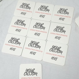 May include: Ten white square coasters with black text that reads "Your Custom" and "Logo/Text/Photo Here".
