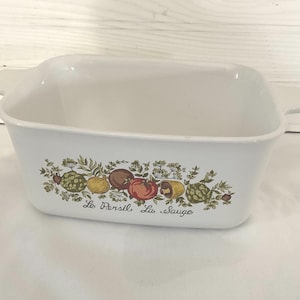May include: White rectangular baking dish with handles, decorated with a colorful fruit and vegetable design. The words "La Persil La Sauge" are printed below the design.