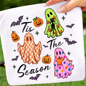 K&ouml;nnte beinhalten: Ein wei&szlig;es T-Shirt mit einer Halloween-Grafik und dem Text "Tis The Season". Das Design zeigt drei Geister: einen lindgr&uuml;nen mit einer schwarzen Katze, einen orange-wei&szlig; karierten und einen rosa Geist mit bunten Punkten, dazu K&uuml;rbisse und Flederm&auml;use.