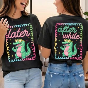 May include: Black t-shirts with a colorful graphic of a cartoon alligator wearing heart-shaped sunglasses. One shirt says "later" and the other says "after while". The alligator is green with a pink belly.