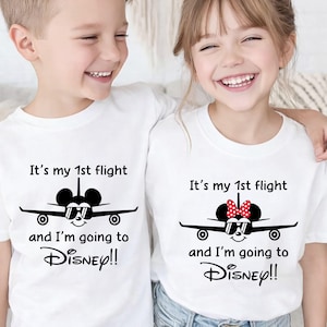 May include: Two white t-shirts with a black graphic of an airplane with a Mickey Mouse head wearing sunglasses. The text reads "It's my 1st flight and I'm going to Disney!!". One shirt has a Minnie Mouse bow.