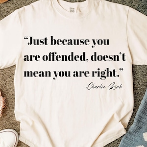May include: Cream-colored t-shirt with the quote "Just because you are offended, doesn't mean you are right." in black text. The author's name, Charlie Kirk, is below the quote. The shirt is made of a soft material.