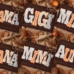 May include: A collection of dark brown shirts featuring block letters that spell out MAMA, GIGI, MINI, NANA, MIMI, and AUNT. Each letter is filled with a patterned design of orange plaid, blue plaid, or autumn leaves, and each shirt includes a jute twine bow.