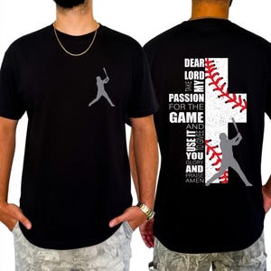 Könnte beinhalten: Schwarzes T-Shirt mit einer grauen Baseballspieler-Silhouette auf der Vorderseite. Auf der Rückseite des Shirts befindet sich ein weißes Kreuz mit roten Baseballnähten und dem Text: "Lieber Herr, nimm meine Leidenschaft..."