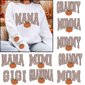 May include: A white long-sleeve sweatshirt featuring the word MAMA in a brown and white plaid pattern with an orange pumpkin graphic. The sleeve displays the names Jessica and Caiden in black script, each accompanied by a small orange pumpkin.