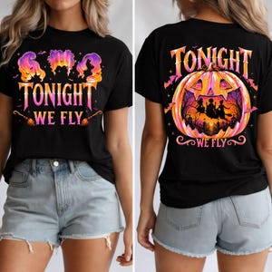 May include: A black t-shirt featuring a graphic print with the text "TONIGHT WE FLY" in pink and orange gradient lettering. The front shows three silhouettes, while the back displays a large pumpkin containing a scene of three witches on brooms.