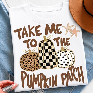 May include: A white t-shirt featuring the brown text TAKE ME TO THE PUMPKIN PATCH and two light brown stars. The design includes three pumpkins: one with a brown leopard print, one with a black and white checkerboard pattern, and one with black dots.