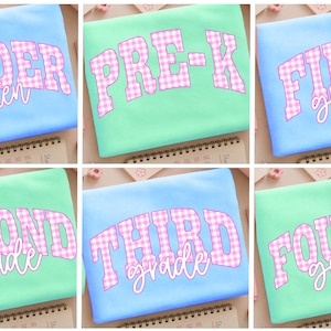 May include: A collection of six rectangular fabric pouches in light blue and mint green. Each pouch features a large, pink and white gingham patterned text graphic displaying school grade levels including Kinder, Pre-K, First, Second, Third, and Fourth grade.