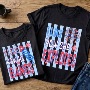 May include: Two black t-shirts with patriotic graphics. One shirt says "I LIKE HOW HE BANGS" and the other says "I LIKE HOW SHE EXPLODES" in red and blue text. The shirts have a blue and white striped background.
