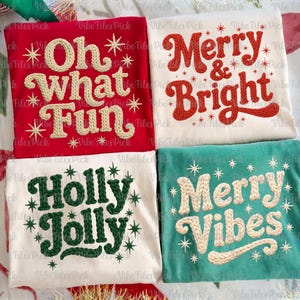 May include: Four Christmas-themed shirts with embroidered text. The shirts are red, white, and teal, with phrases like "Oh What Fun," "Merry & Bright," "Holly Jolly," and "Merry Vibes." Each shirt features star accents.