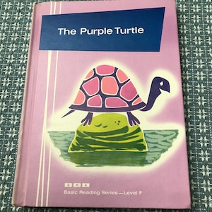 May include: A children's book titled "The Purple Turtle" with a purple cover. The cover features a cartoon turtle with a pink and purple shell, standing on a green rock. The book is part of the "Basic Reading Series - Level F".