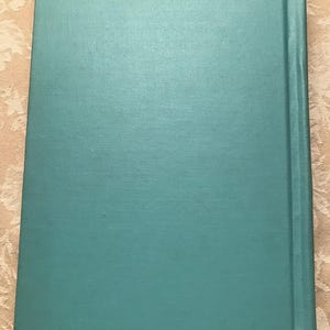 Puede incluir: Un libro de color turquesa con una cubierta texturizada. El lomo es de un tono turquesa m&aacute;s oscuro. La cubierta del libro tiene una apariencia ligeramente rugosa y tejida.