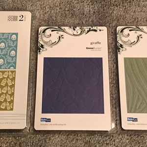 May include: Three embossing die sets. The first set is labeled "Birds of a Feather" with two patterned designs. The second set is labeled "giraffe" with a textured design. The third set is labeled "zebra" with a striped design.
