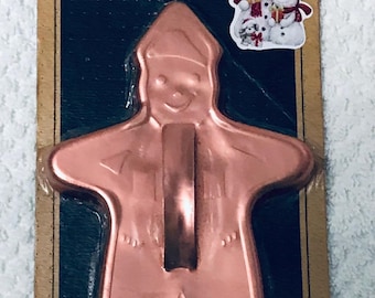 May include: Vintage copper gingerbread boy cookie cutter on a cardboard backing. The cutter is in the shape of a gingerbread man with a smiling face. The packaging includes the text "EASY DO" and a snowman sticker.