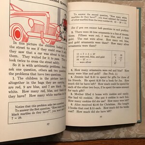 Puede incluir: Libro abierto con problemas de aritm&eacute;tica. La p&aacute;gina 92 muestra una ilustraci&oacute;n de un coche y un problema de palabras sobre canicas. La p&aacute;gina 93 incluye m&aacute;s problemas de matem&aacute;ticas sobre adornos, regalos y galletas. El texto es negro.