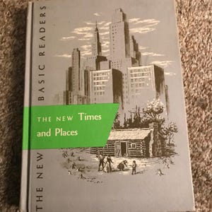May include: A hardcover book titled Basic Readers The New Times and Places with a gray cover featuring a black and white illustration of a city skyline above a log cabin with figures in the foreground and a bright green horizontal band.