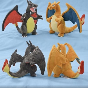 May include: Four plush dragon toys in various poses. Two are orange with blue wings, and two are dark gray with red wings. All have yellow bellies and flame-tipped tails. The toys are on a light blue background.
