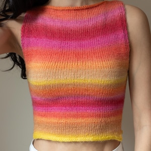 Puede incluir: Un top sin mangas tejido con un vibrante degradado de colores. El top pasa del amarillo en la parte inferior al naranja, rosa y rojo en la parte superior. La prenda tiene un cuello redondo simple y una silueta ajustada.