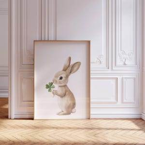 May include: A watercolor illustration of a brown rabbit holding a green four-leaf clover. The rabbit is standing on a white background.