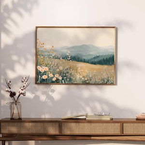 Könnte beinhalten: Ein gerahmter Druck eines Aquarells, das eine Wildblumenwiese im Vordergrund mit einem Gebirge im Hintergrund zeigt. Der Himmel ist hellblau mit einem Hauch von Wolken. Die Berge sind in einem sanften Grün und Blau gehalten.