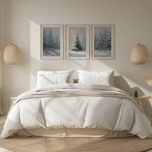 May include: A bedroom scene featuring a bed with white bedding, pillows, and a beige throw. Above the bed are three framed winter landscape paintings. Woven pendant lights hang on either side of the bed, and a round rug sits beneath.