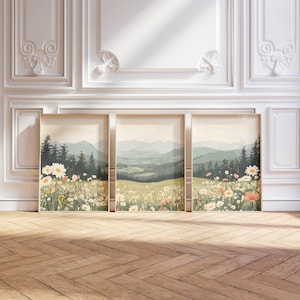 Peut inclure: Trois impressions d'art encadrées représentant des paysages. Chaque impression montre une scène de prairie avec des fleurs sauvages, des arbres et des collines sous un ciel doux. Les cadres sont de couleur bois clair.