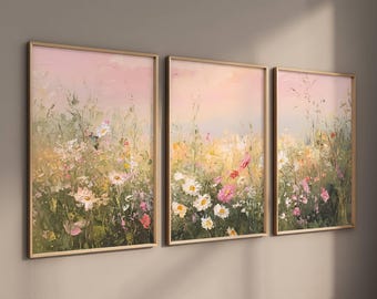 May include: Three framed floral art prints. The artwork features a field of wildflowers in shades of pink, white, yellow, and green. The background has a soft pink and yellow gradient. The frames are a light wood color.