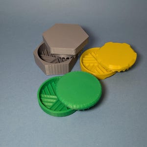 May include: Three 3D printed hexagonal boxes with lids. The boxes are gray, green, and yellow. The lids have a geometric pattern.