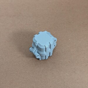 May include: A light blue plastic box with a square shape and a textured surface. The box has a series of small holes on the sides.