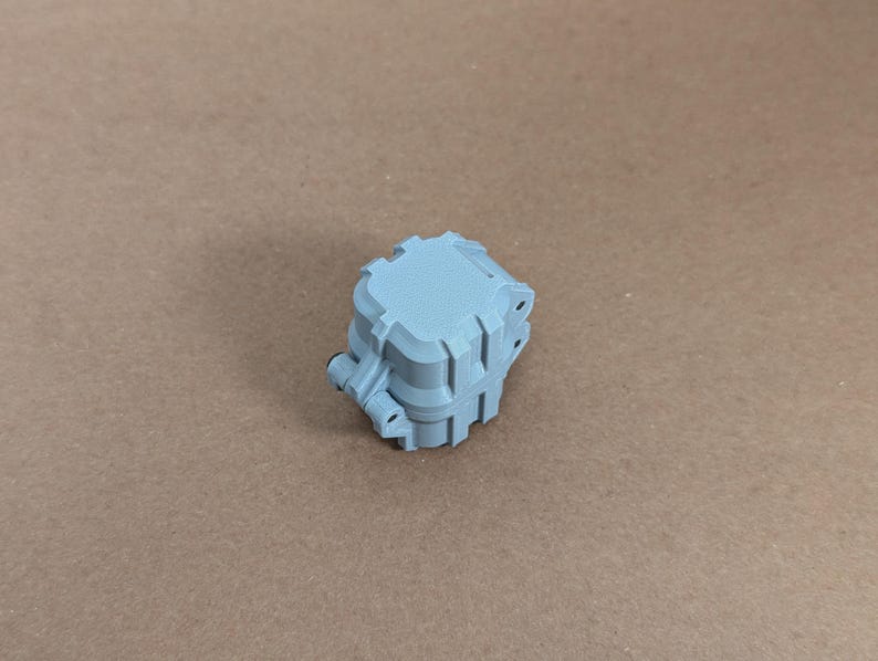 May include: A light blue plastic box with a square shape and a textured surface. The box has a series of small holes on the sides.