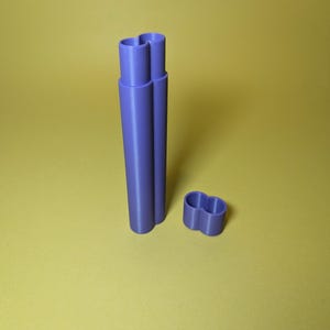 May include: A purple plastic container with two compartments. The container is open and the top part is separate.