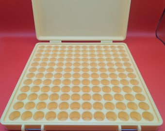 May include: A yellow plastic storage box with a hinged lid and a grid of 100 round compartments. The box is open and the compartments are empty.