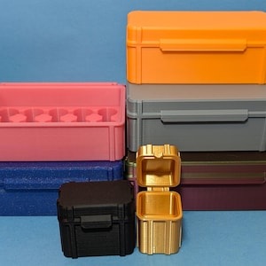 May include: A set of six storage boxes in various colors, including orange, gray, pink, blue, and black. The boxes are made of plastic and have a variety of sizes and shapes. The boxes are stacked on top of each other.