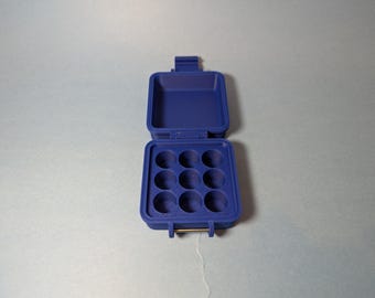 May include: A blue plastic storage case with a hinged lid and nine compartments. The case is open and the compartments are empty.