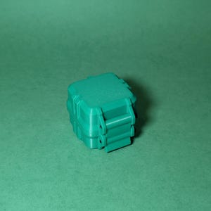 Puede incluir: Una peque&ntilde;a caja de almacenamiento de pl&aacute;stico verde azulado con una tapa con cierre. La caja tiene una superficie texturizada y est&aacute; dise&ntilde;ada para ser impermeable.