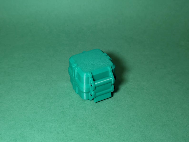 Puede incluir: Una peque&ntilde;a caja de almacenamiento de pl&aacute;stico verde azulado con una tapa con cierre. La caja tiene una superficie texturizada y est&aacute; dise&ntilde;ada para ser impermeable.